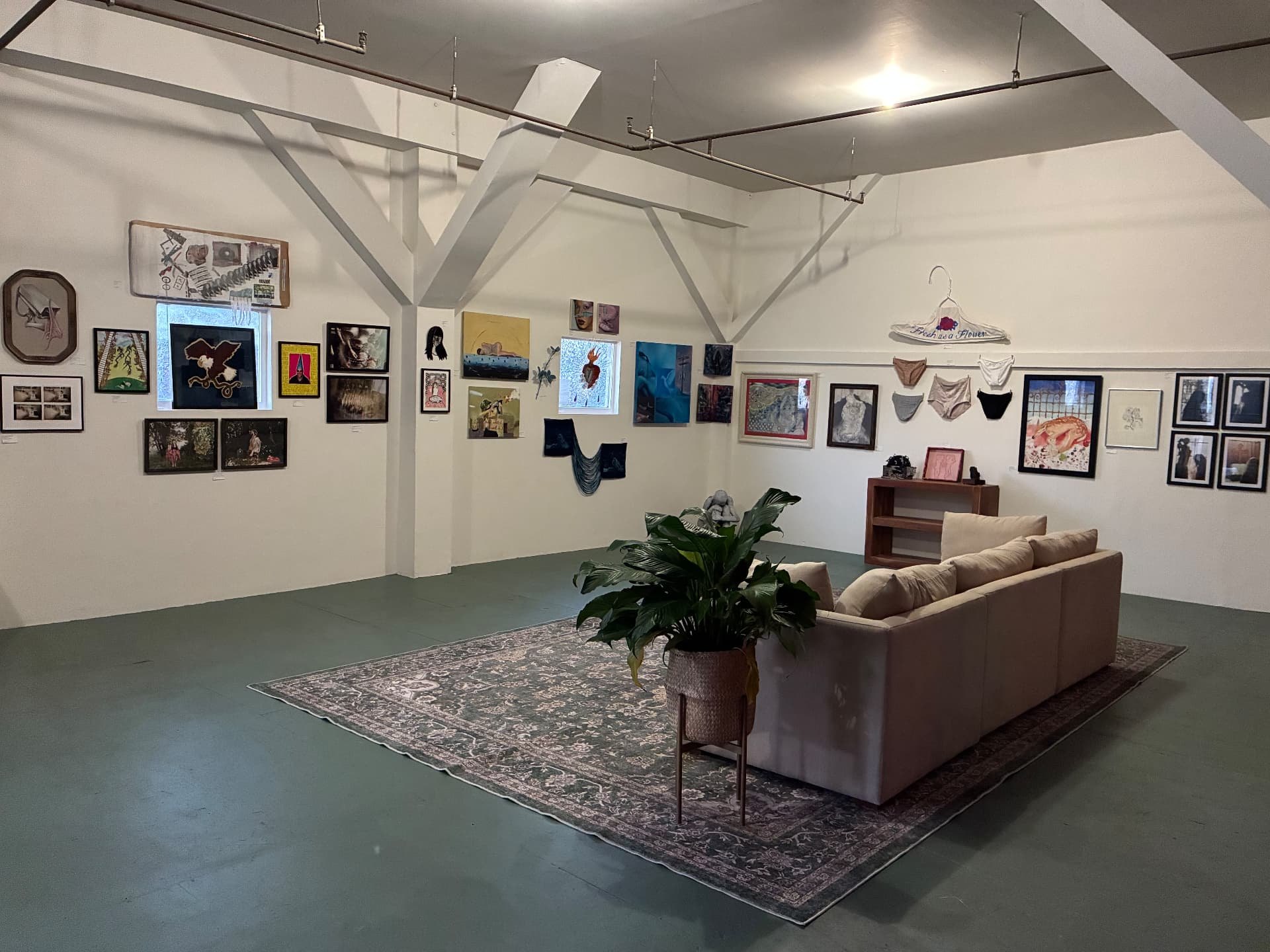 A salon-style hang of dozens of framed artworks across two walls of the Harbor above a sofa and rug