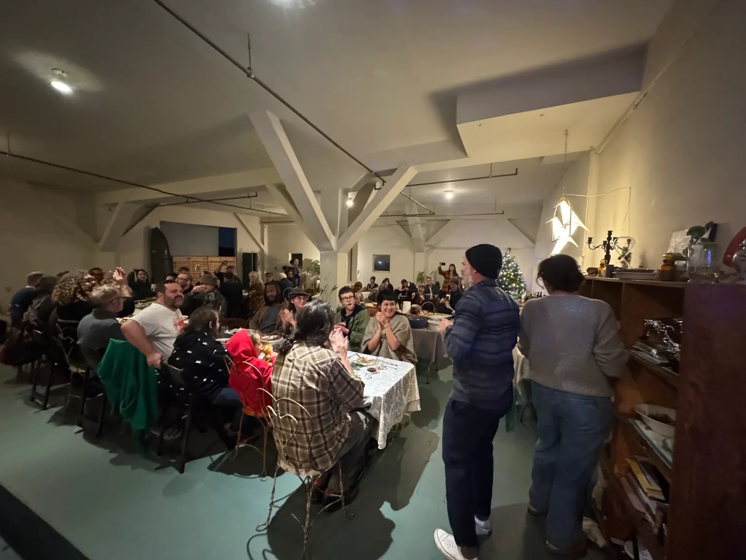 Neighbors packed along the supper table in the Harbor, applauding a toast
