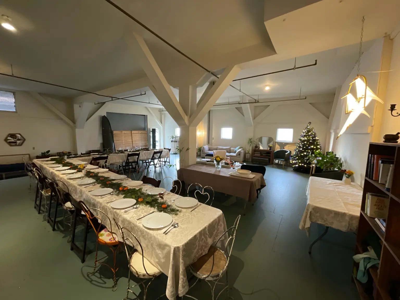 Long tables in white damask linen with greenery and mandarins, a lit tree at the far end of the Harbor
