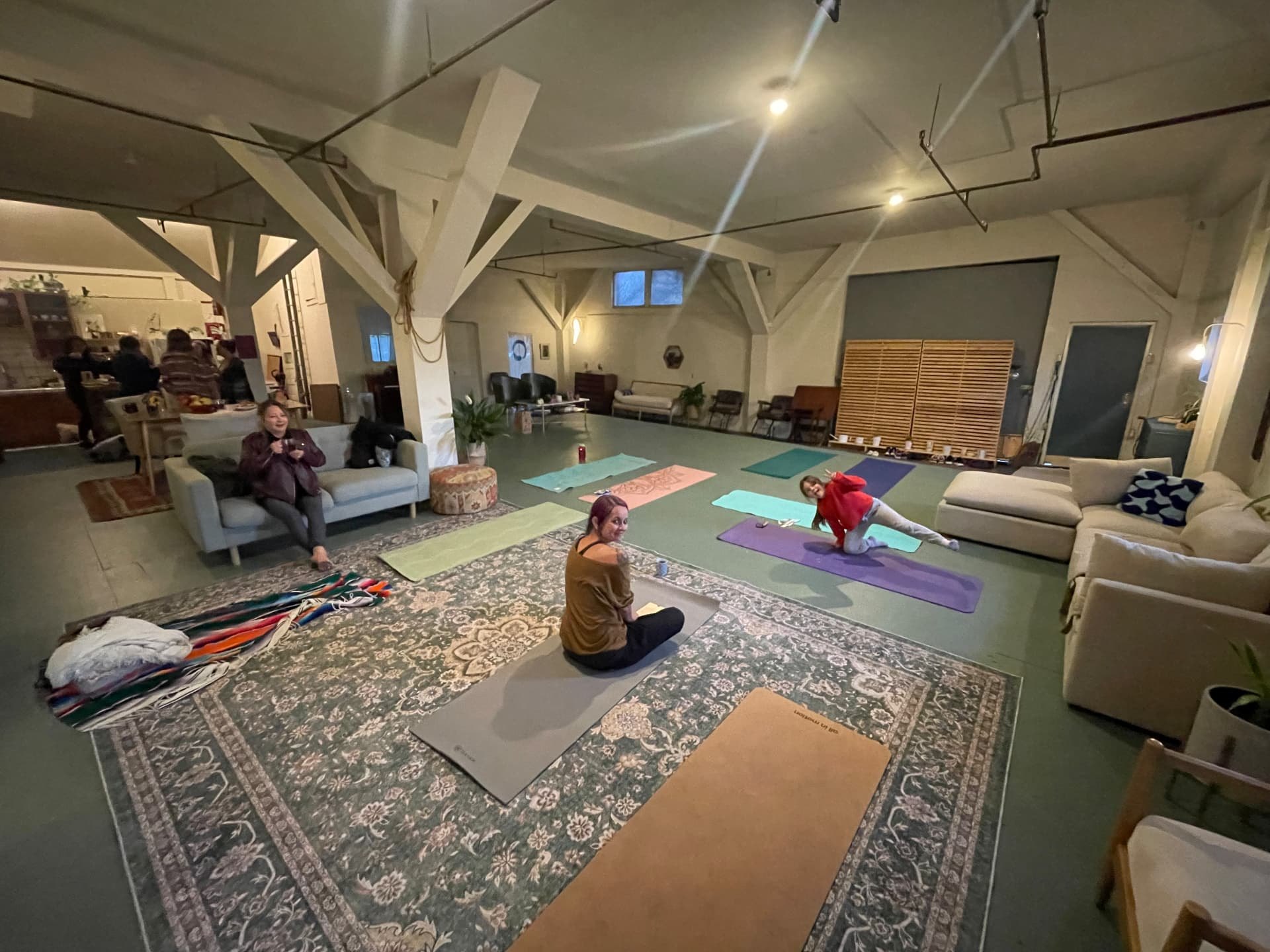 Mats laid out across rugs for an evening yoga class with neighbors on the sofas